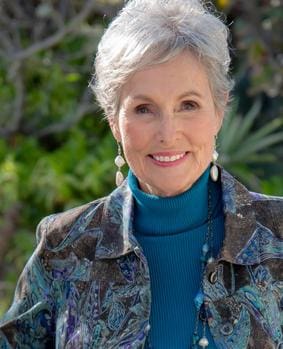 A woman with white hair wearing a blue shirt.