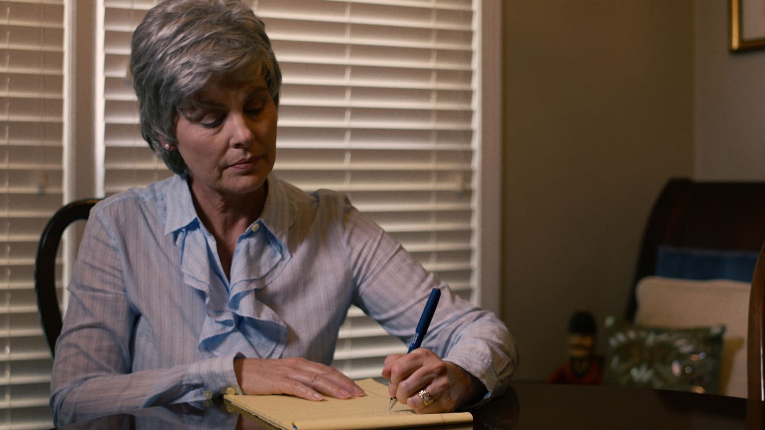 A woman writing on paper at the table.